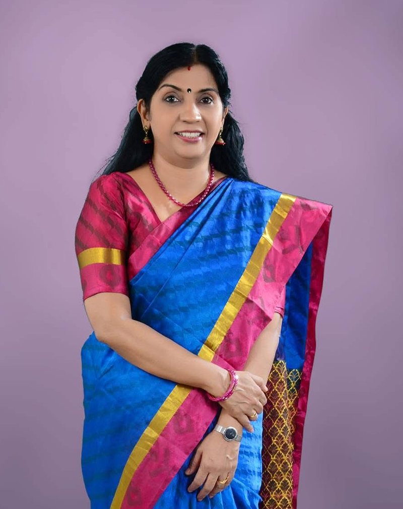 Portrait of Dr. Geetha Nair in a blue silk saree with a pink and gold border